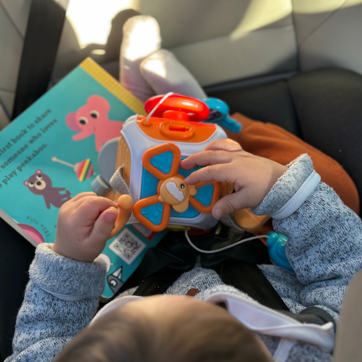 Child playing with a toy in a car seat